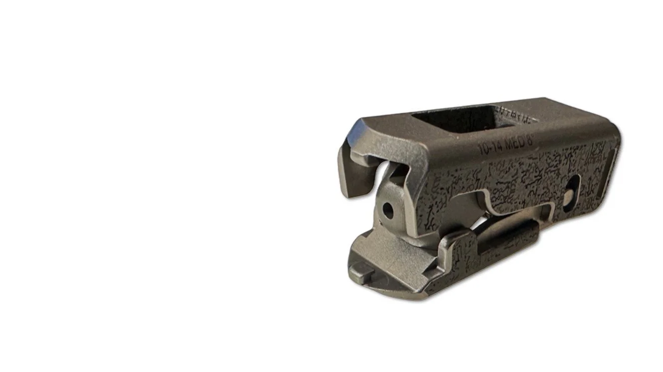 Two expandable lumbar implants with biobraille with rectangular openings, resting on a white surface, casting shadows.
