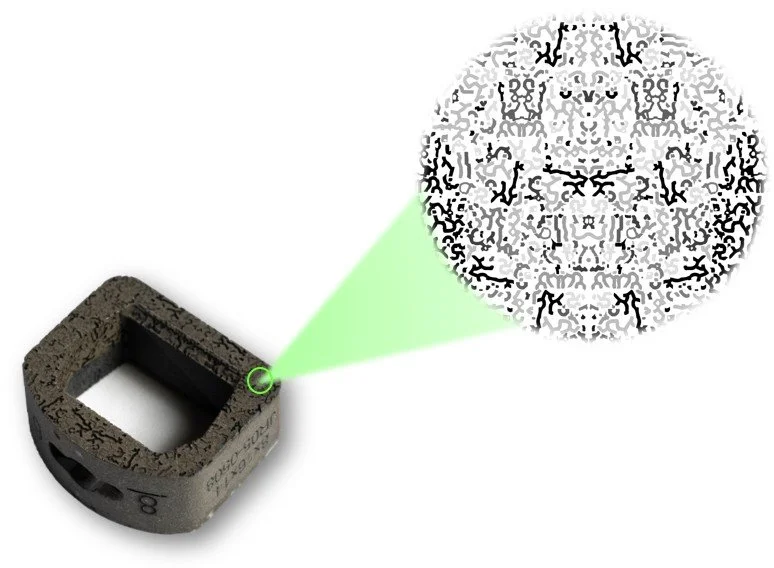 A cervical spacer implant with biobraille with a squared hole, exposing a green laser beam pointed at a surface, creating a symmetrical, black-and-white kaleidoscopic pattern to show biobraille pattern.