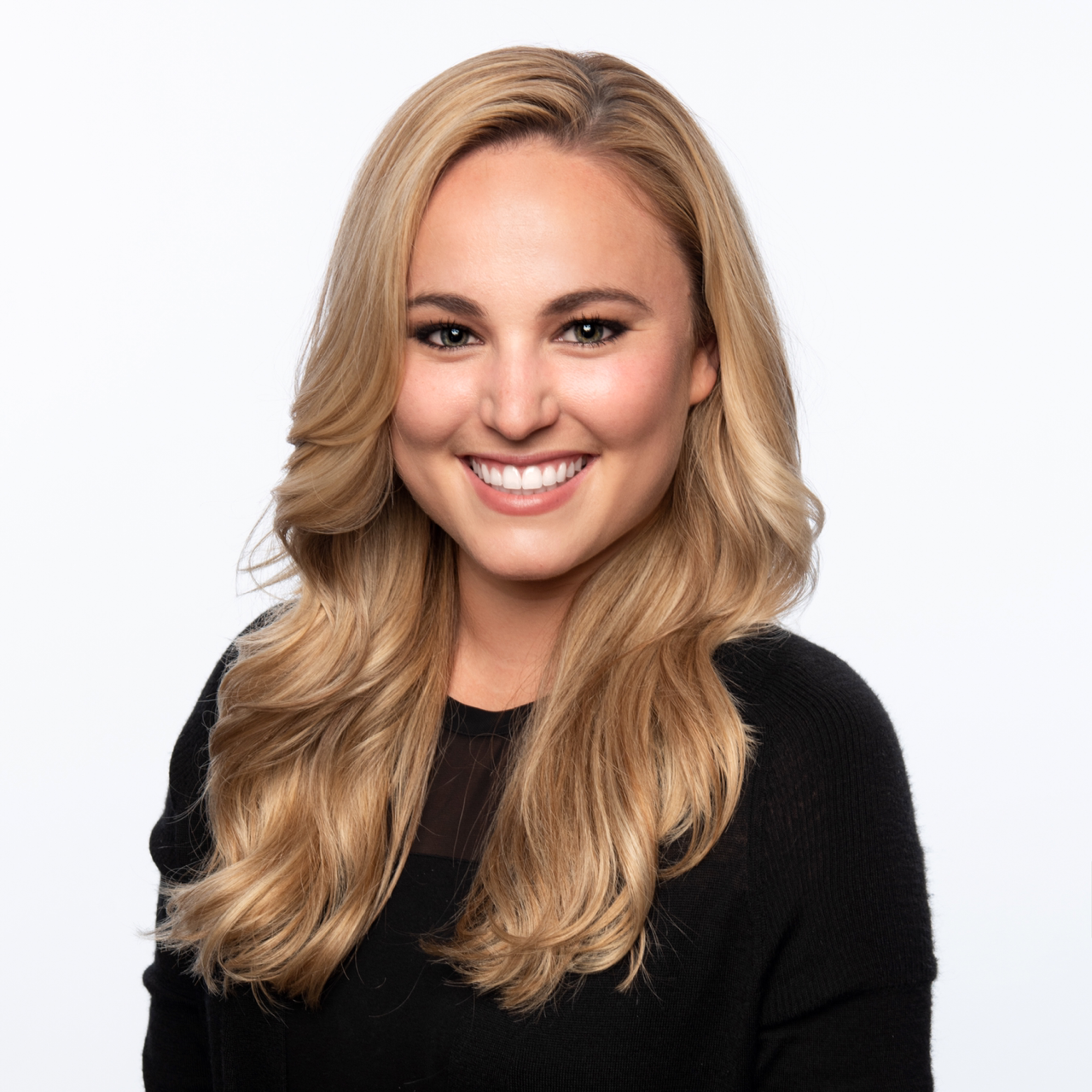 A young woman with long wavy blonde hair, smiling, wearing a black top, against a white background. Melissa Lunsford director of product development and marketing