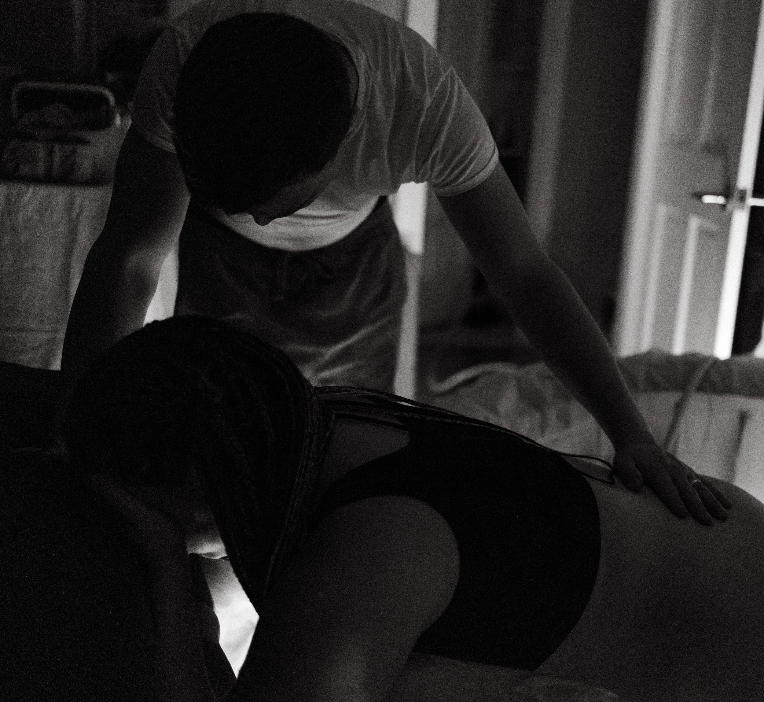 a mother laboring in a birth pool. partner is standing closeby offering comforting touch. the room is dim.