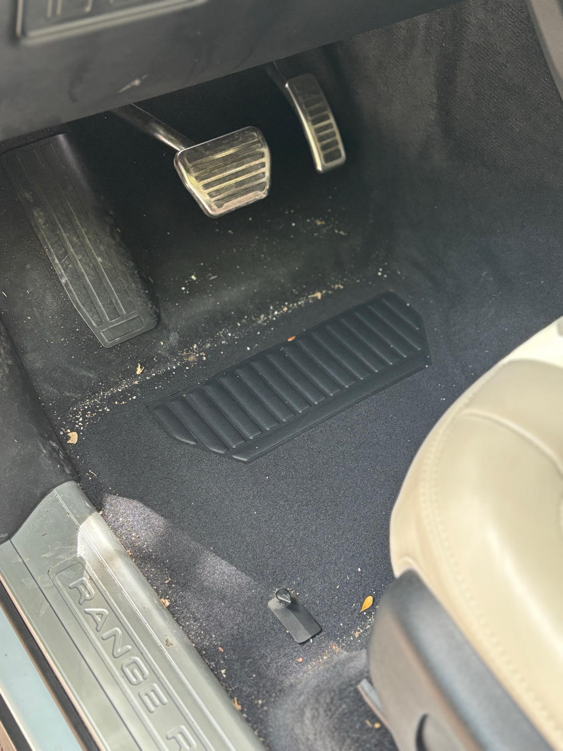 Alt text: Dirty Range Rover carpet before interior car detailing service in North Naples FL showing debris and sand buildup