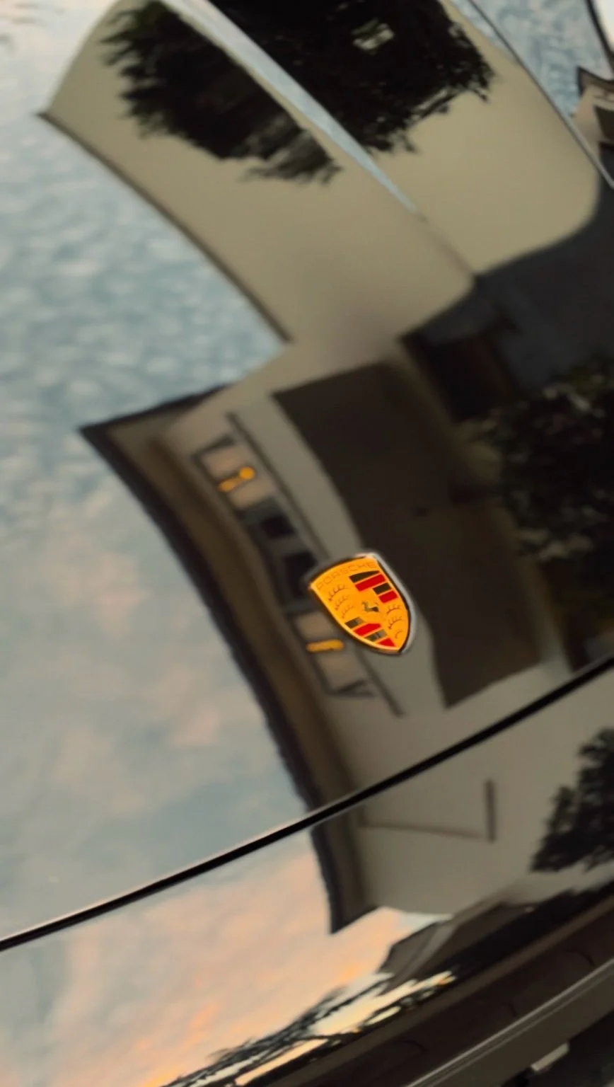 Porsche crest on polished black hood after high-end car detailing service in Naples Florida
