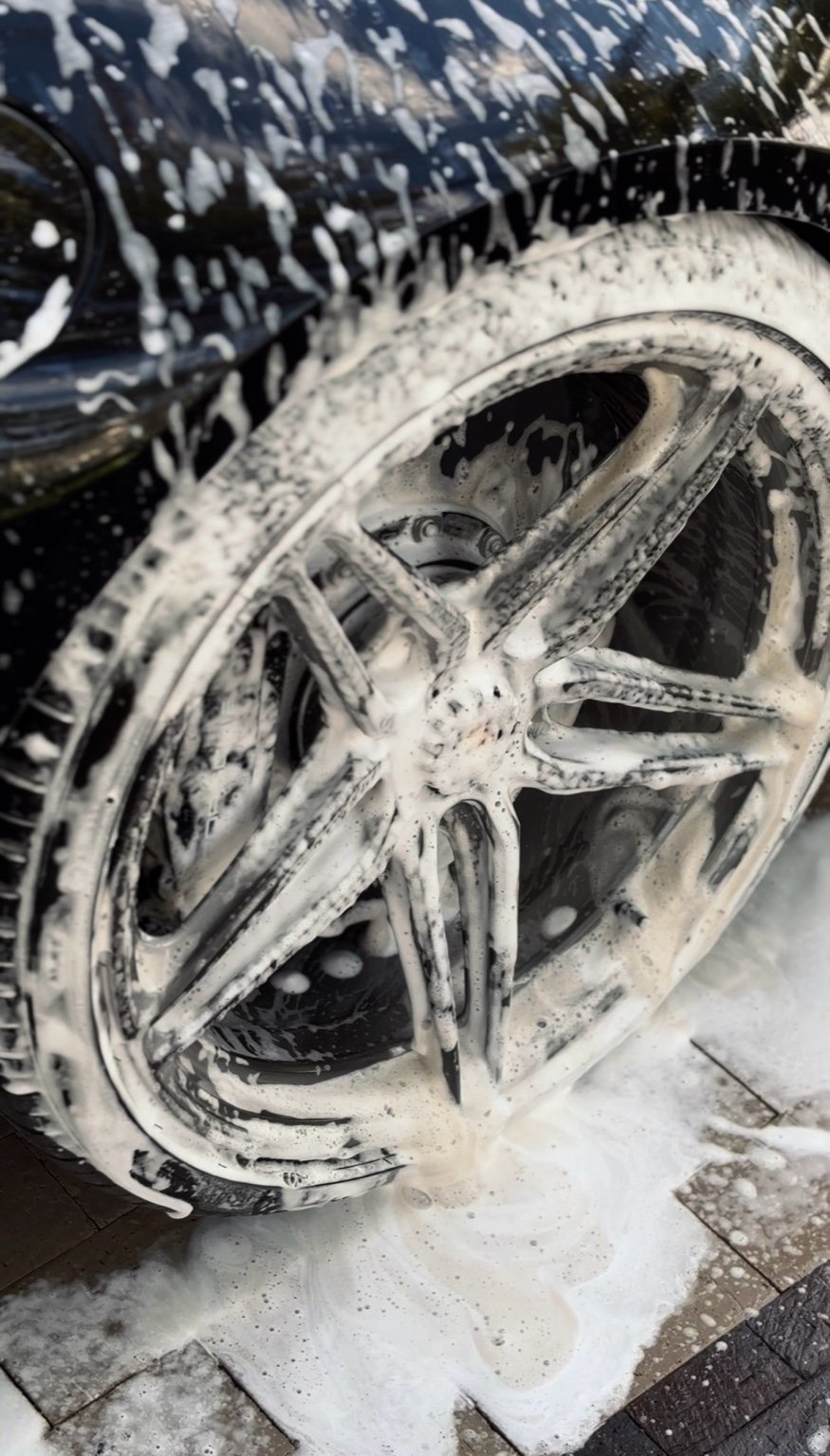 Porsche 911 wheel covered in foam during professional wheel detailing service in Naples FL