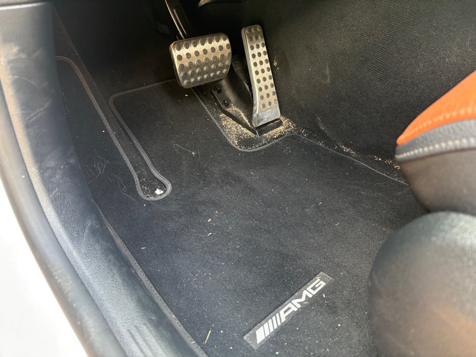 Mercedes AMG driver floor mat before interior car detailing showing sand and debris buildup in Naples Florida
