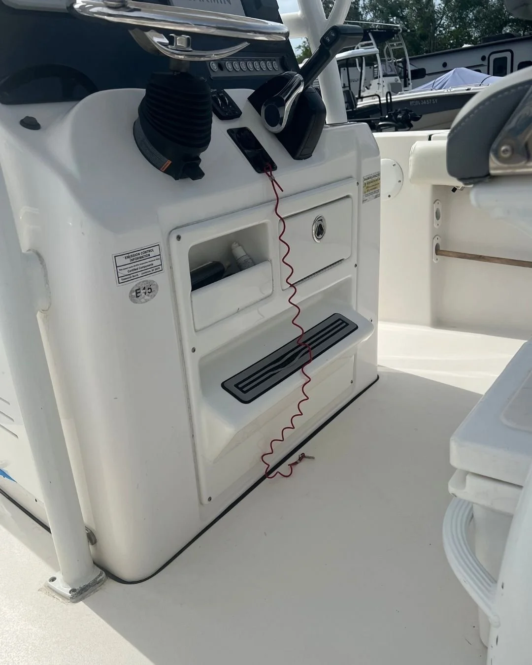 Close-up of a boat's control console with radio, microphone, and storage compartments, surrounded by other boats and water.