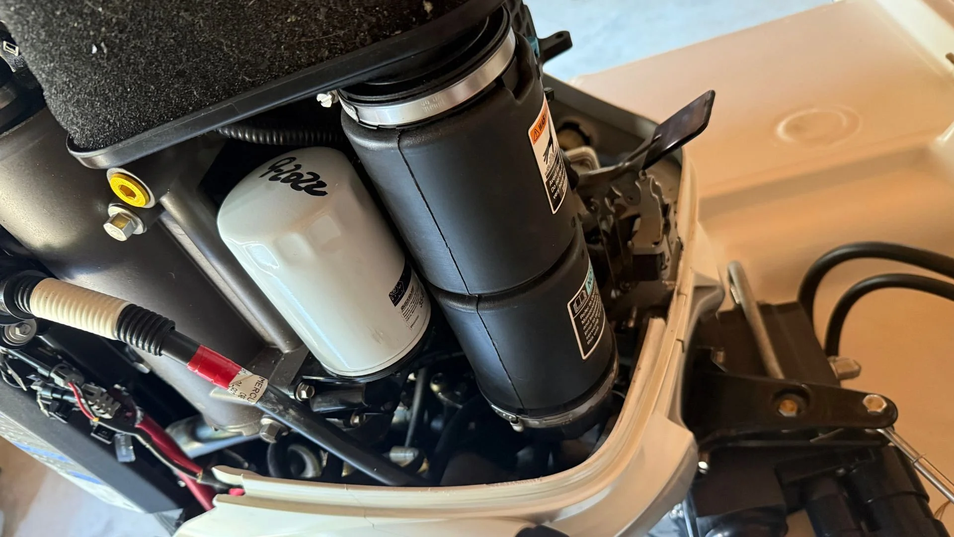 A  boat engine with a rusty flywheel, timing belts, and various components, situated on a grassy outdoor area.