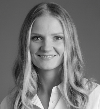 Black and white portrait of a smiling woman with long, wavy hair, wearing a collared shirt.