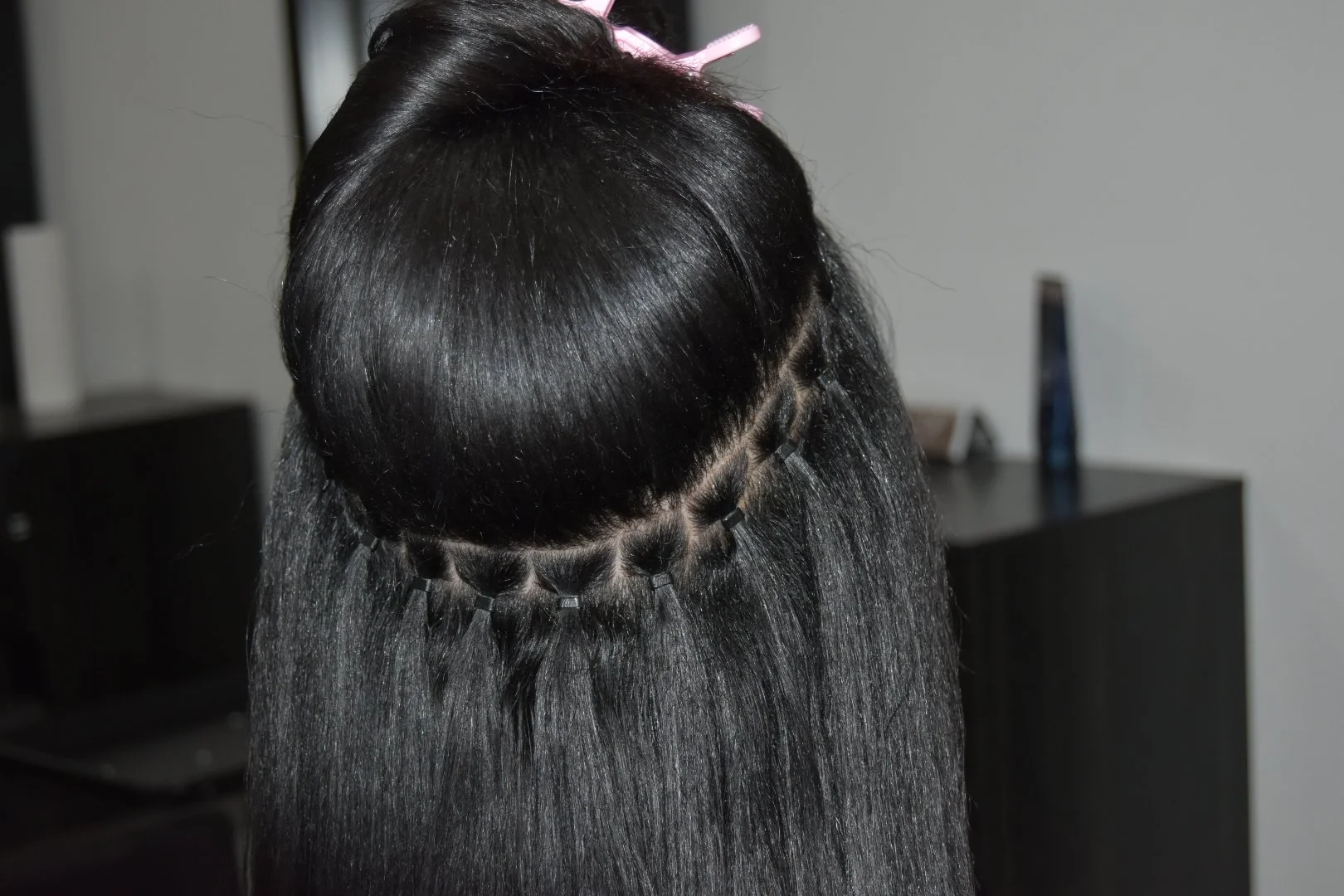 Close-up of a woman with straight black hair, sectioned and clipped in a styling salon.