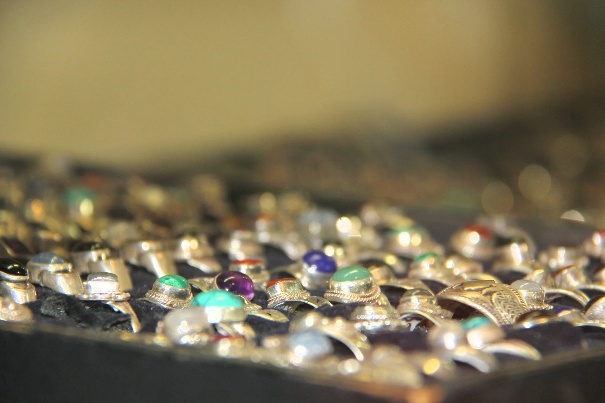 Close-up of various rings with colorful stones displayed on a black surface.