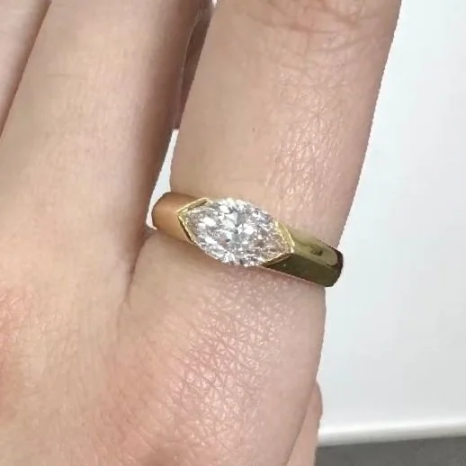 Close-up of a hand wearing a gold ring with a large, marquise-shaped diamond.
