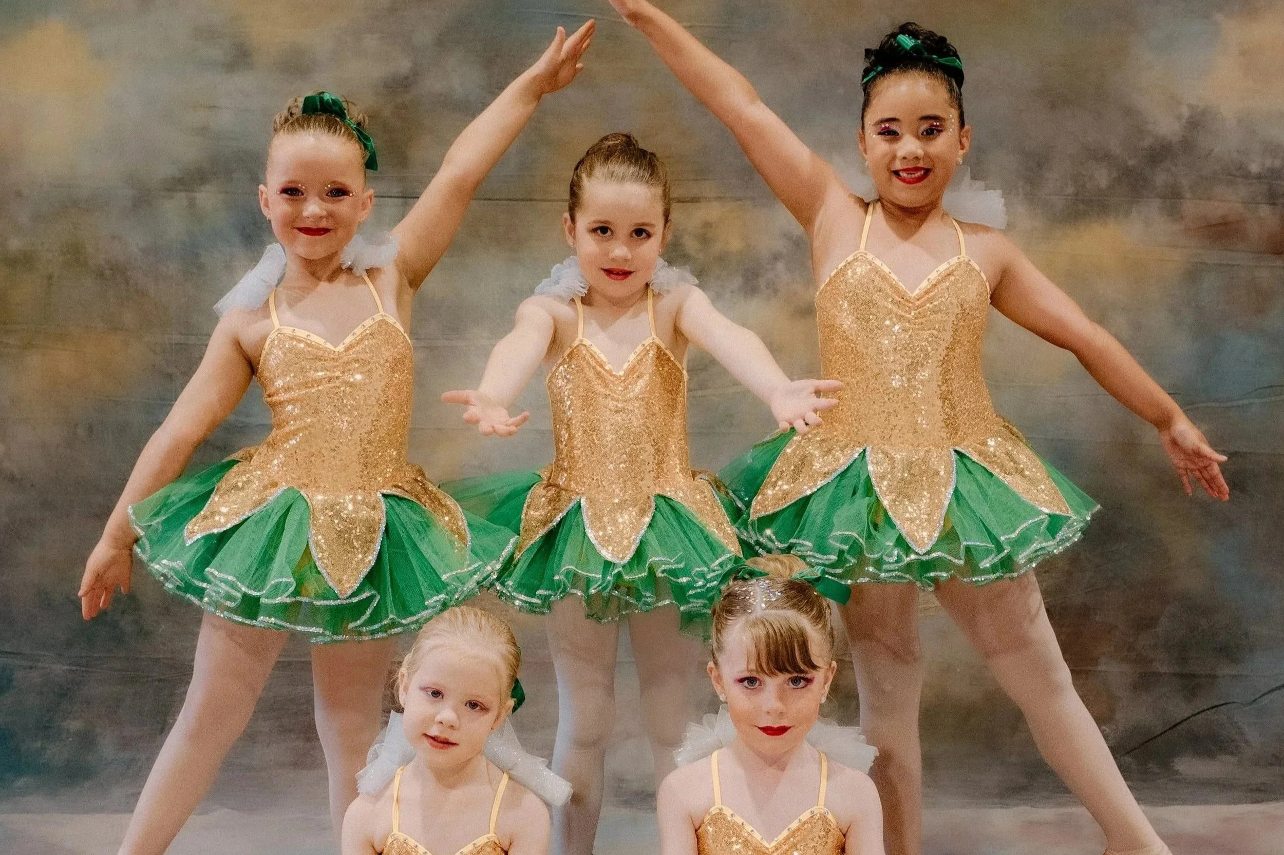 Seven young girls dressed in matching blue sequined ballet costumes with tulle skirts, posing together against a plain background.