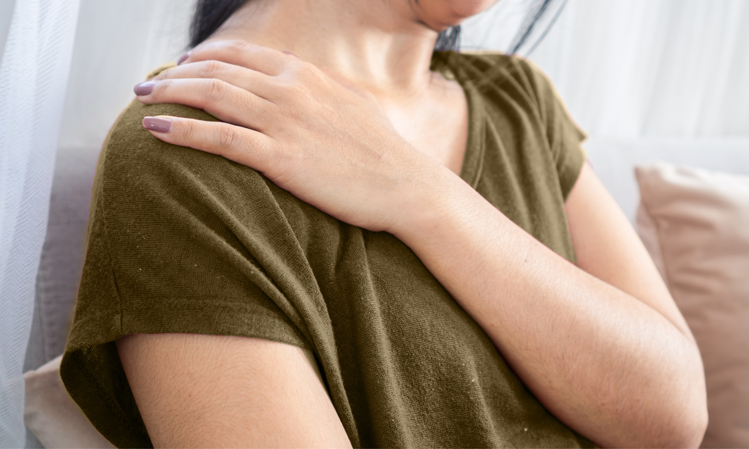 Person holding their shoulder showing neck and shoulder tension associated with stress
