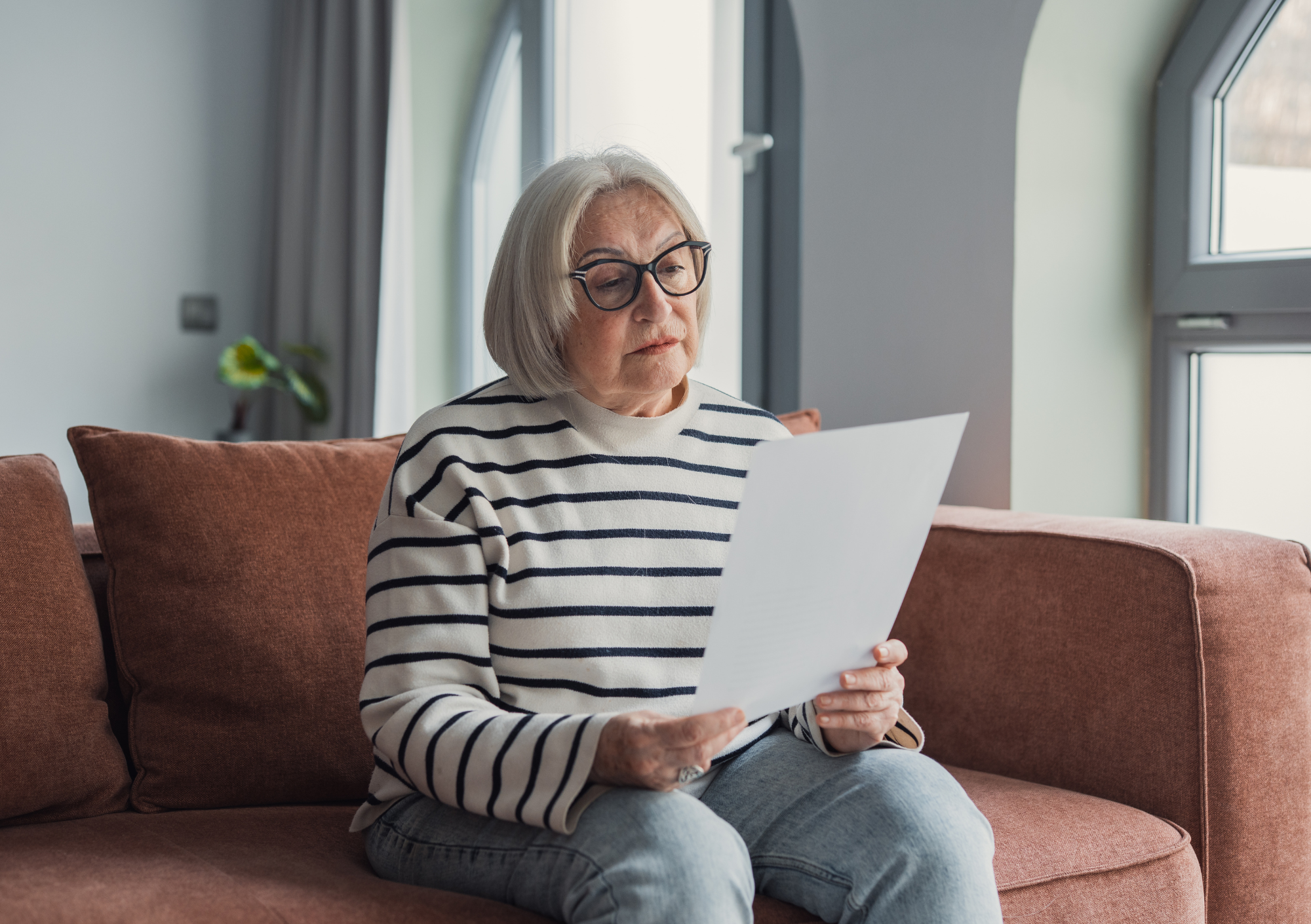 Women reading piece of paper on couch with glasses