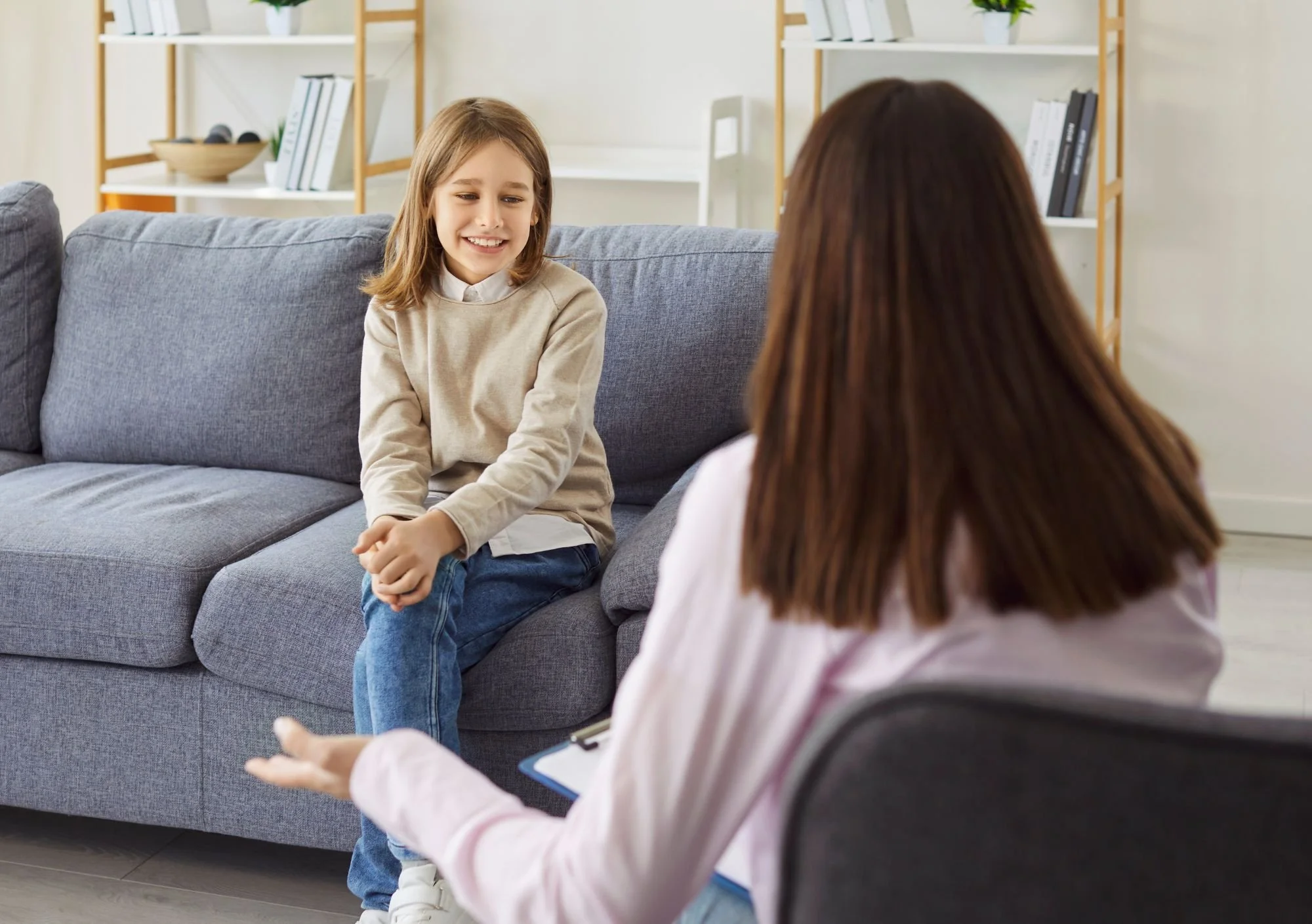 Child sitting on couch with therapist talking to her