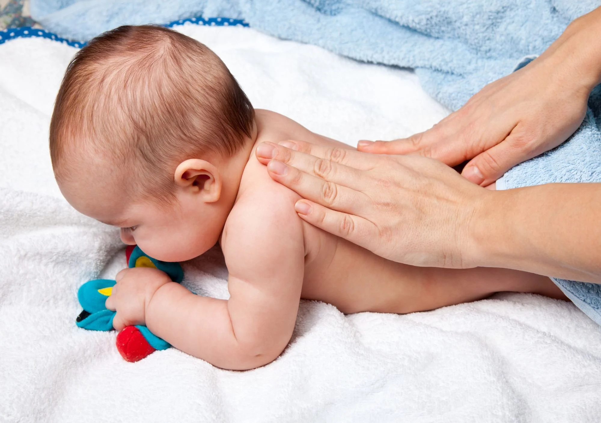 Baby lying on stomach with hands massaging back