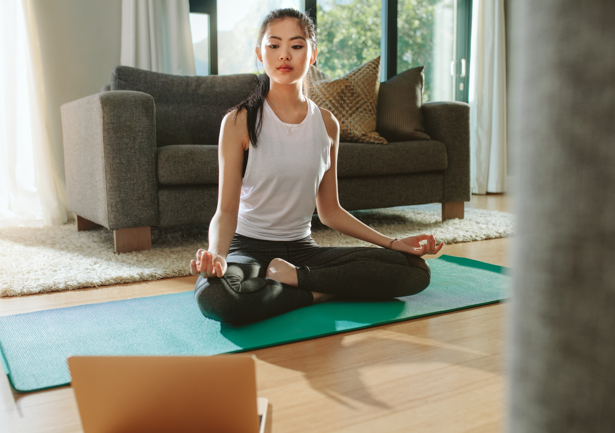 Woman wathching video on laptop in lounge room whilst on exercise mat