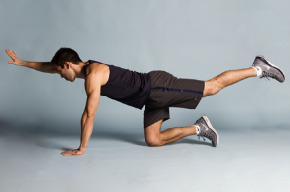 Man performing a balance exercise on all fours with one arm extended forward and opposite leg extended back.
