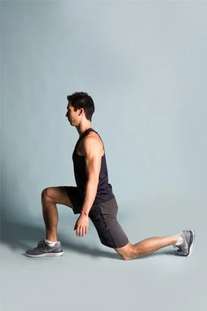 A man in athletic clothing performing a lunge exercise against a plain light blue background.
