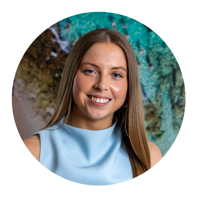 Young woman with long brown hair smiling, wearing a light blue sleeveless top, with an abstract colorful background.