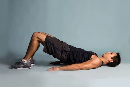 A man performing a leg lift exercise on a gray background.