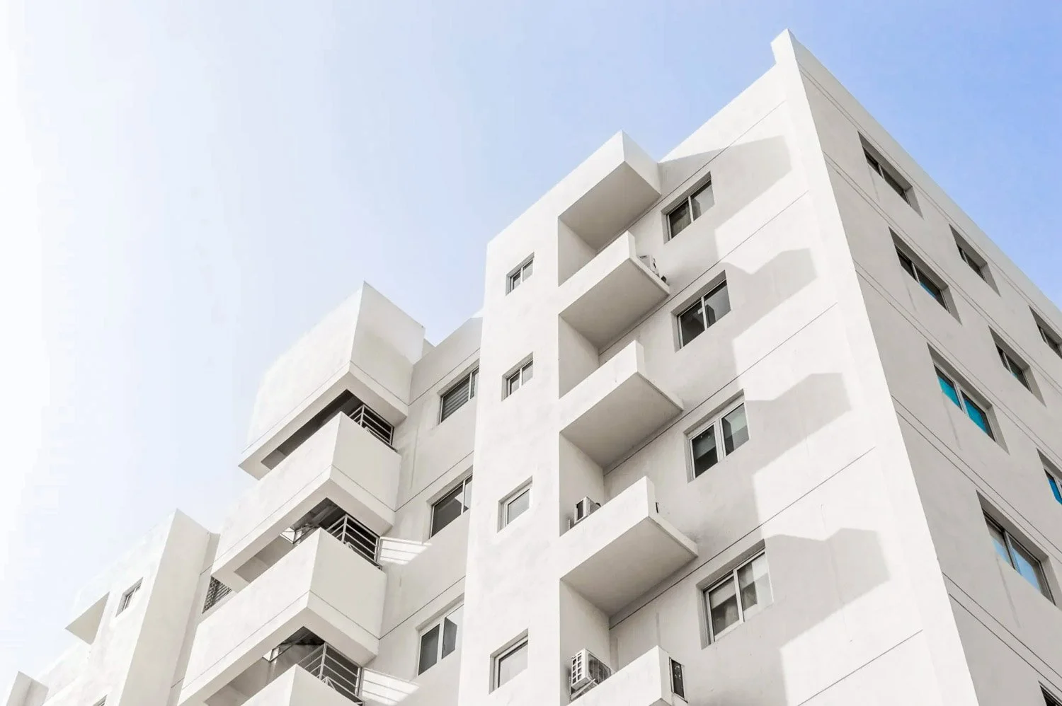 Immeuble blanc toulousain rénové suite à sinistre à Toulouse avec plusieurs fenêtres et balcons, sous un ciel clair.