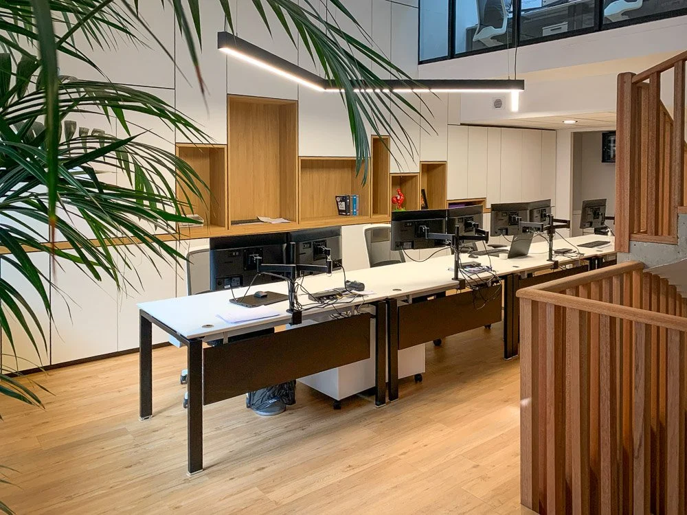 Conception et fabrication de Bureaux sur-mesure avec quatre postes de travail informatiques, , escalier en bois, grande plante verte dans un espace moderne