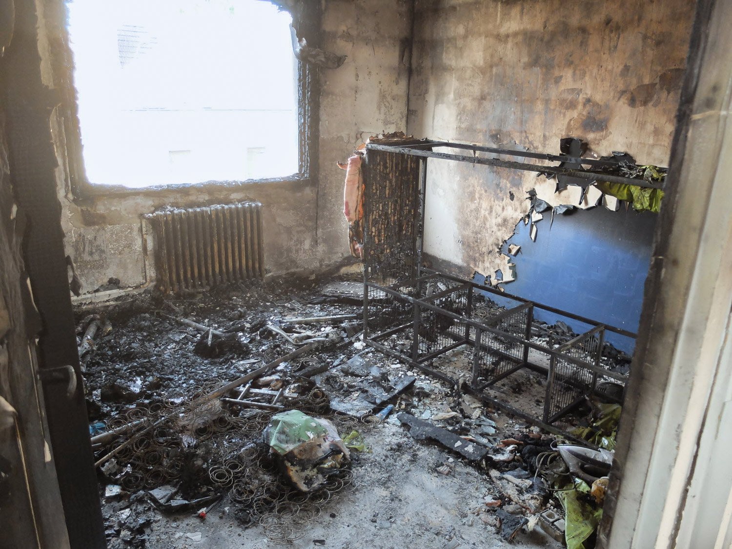 Pièce d'immeuble toulousain détruite par un incendie, meuble brûlé, murs noircis, fenêtres sales