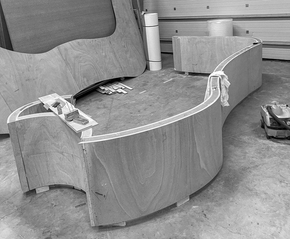 Menuisier Toulouse, une pièce en construction avec un comptoir en bois courbé, des outils et matériaux de menuiserie.