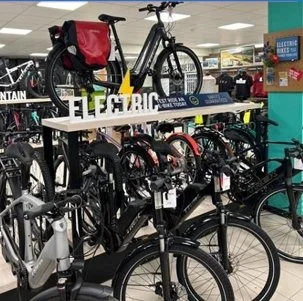 Multiple bicycles displayed on store racks inside a retail store, with some bikes elevated on a stand.