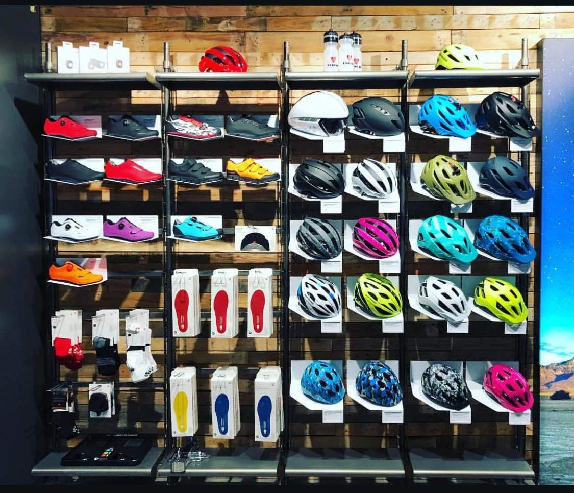 Display of cycling helmets, shoes, and accessories on a wooden wall.