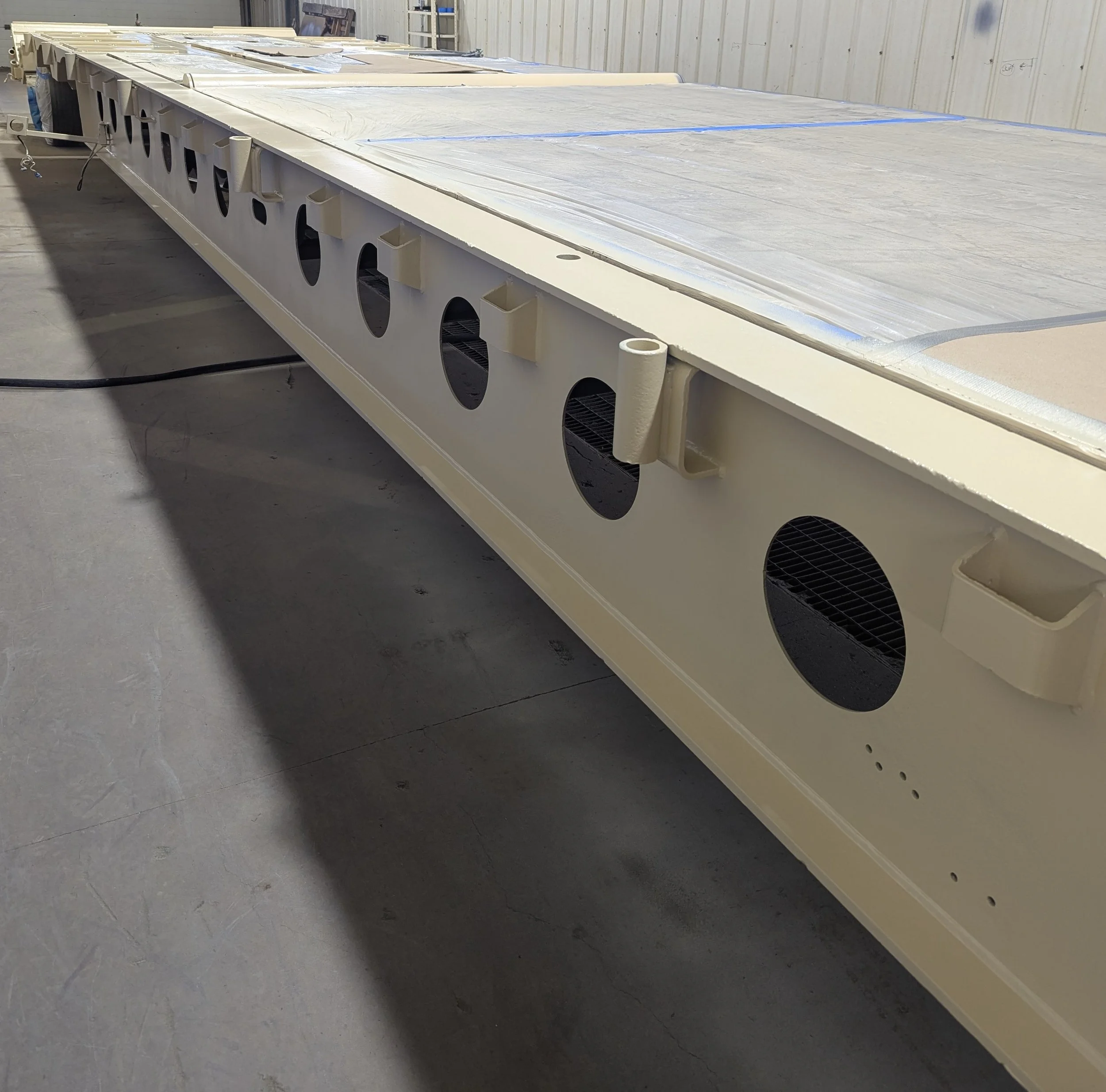 A large industrial or scientific equipment with multiple circular vents and attached components, situated in a workshop or manufacturing facility.