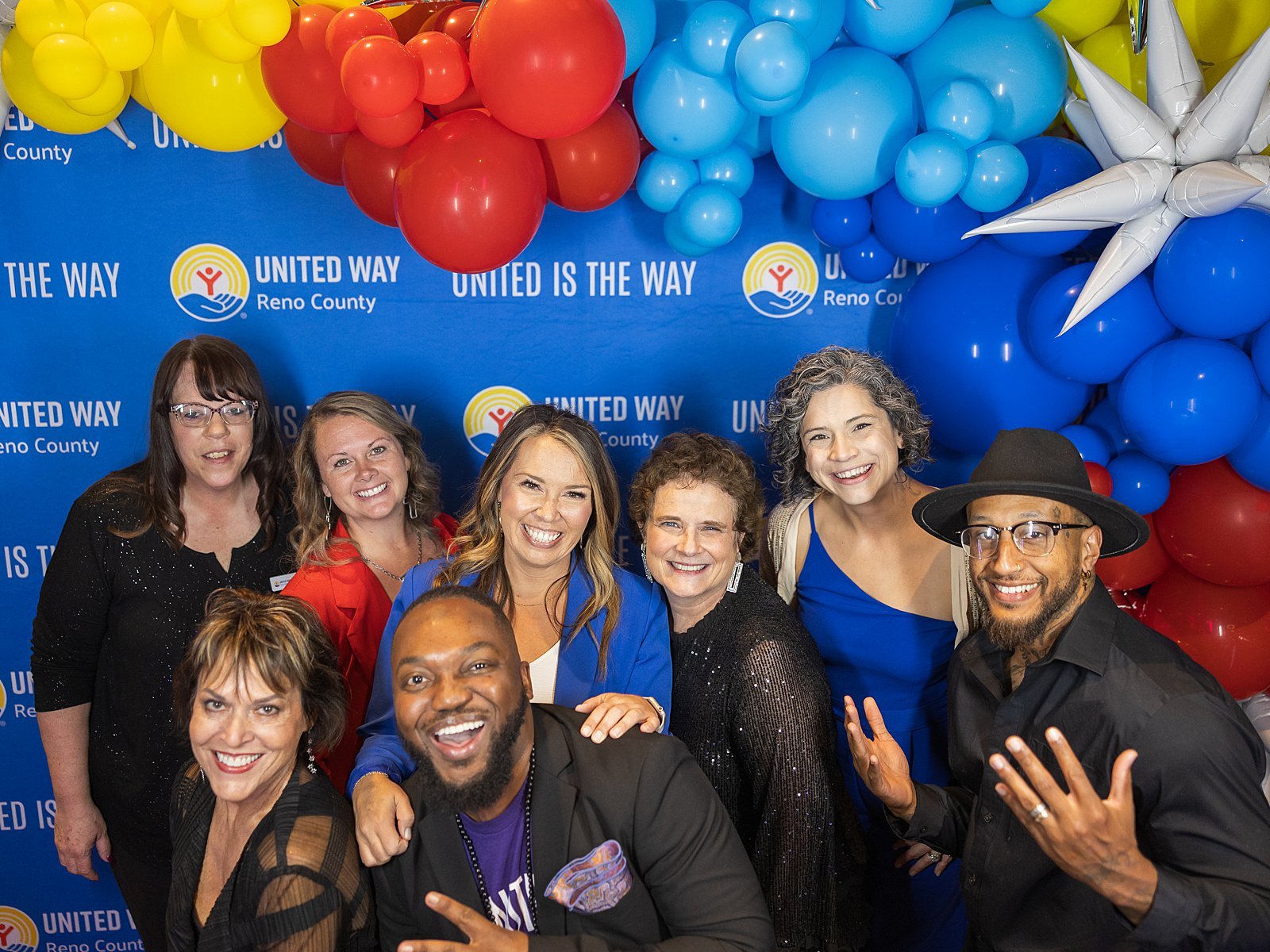 Group of people smiling at a celebration event with a backdrop that says 'United Way Reno County' and colorful balloons.