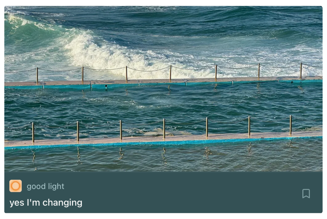 Swimming pool with floating barriers in the foreground and ocean waves in the background.