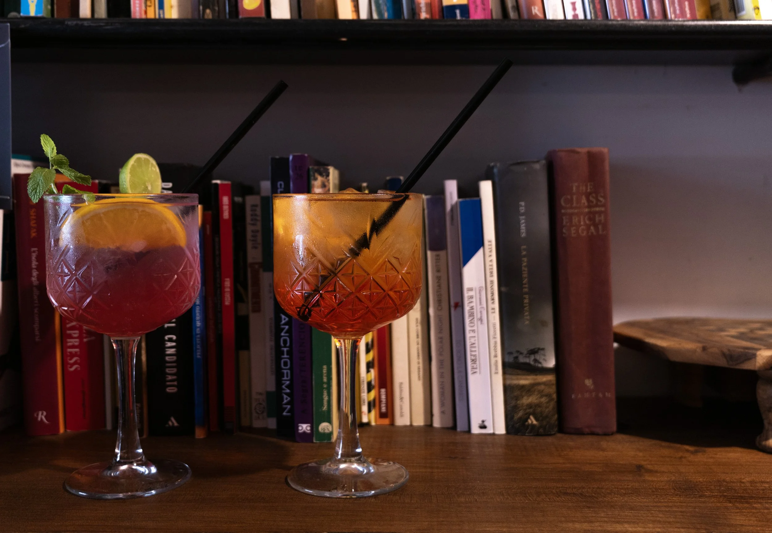 Due cocktails di frutta con canne in un bar, sfondo di scaffale con libri.