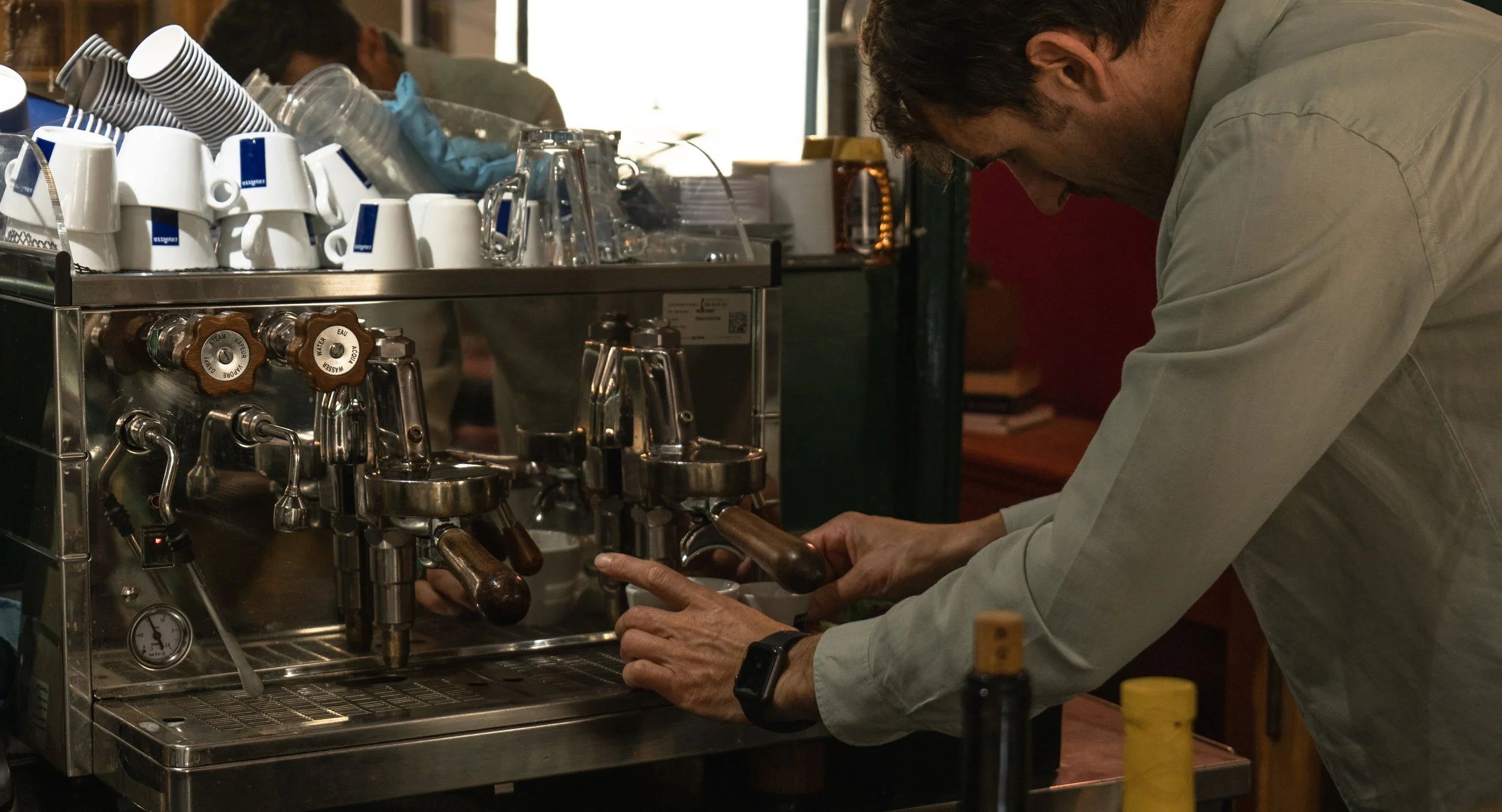 Uomo che prepara un caffè con una macchina da caffè professionale in un bar.