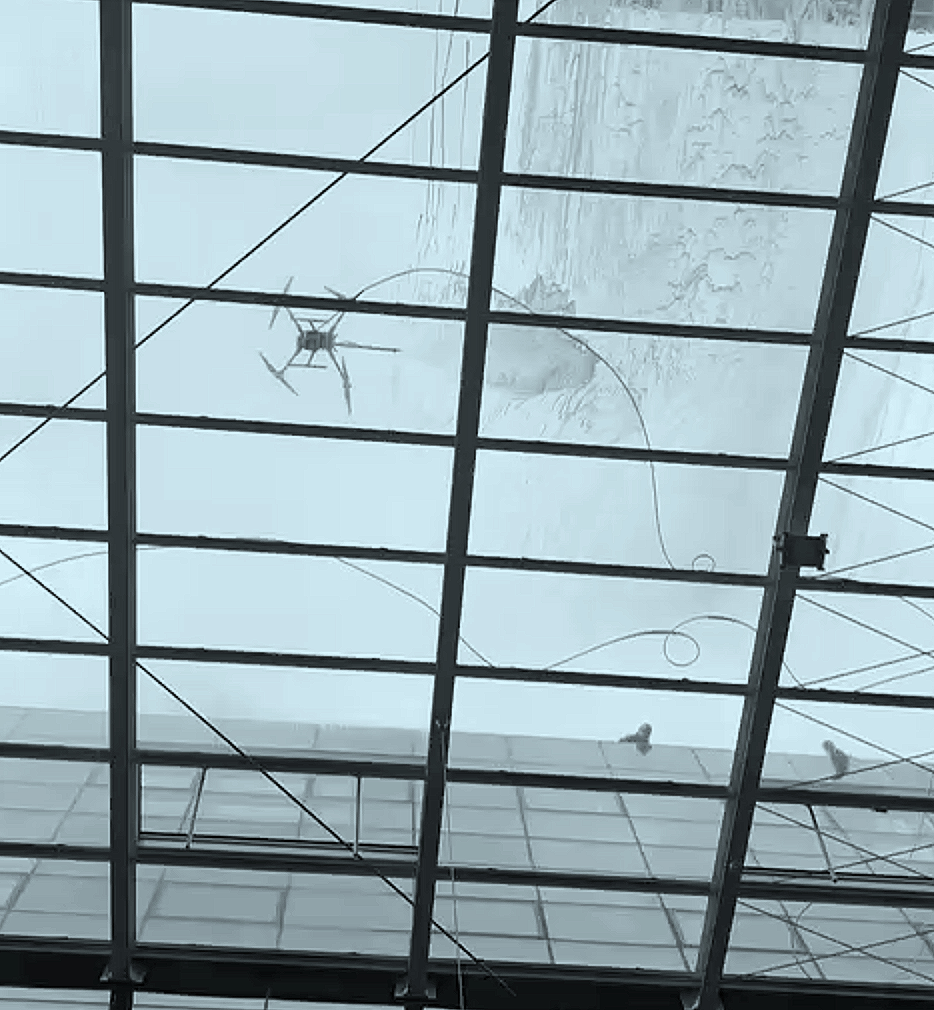 Decke eines Gebäudes mit einer Glasplatte und einem Wasserfleck, sowie eine Abluftventilator und Kabel.