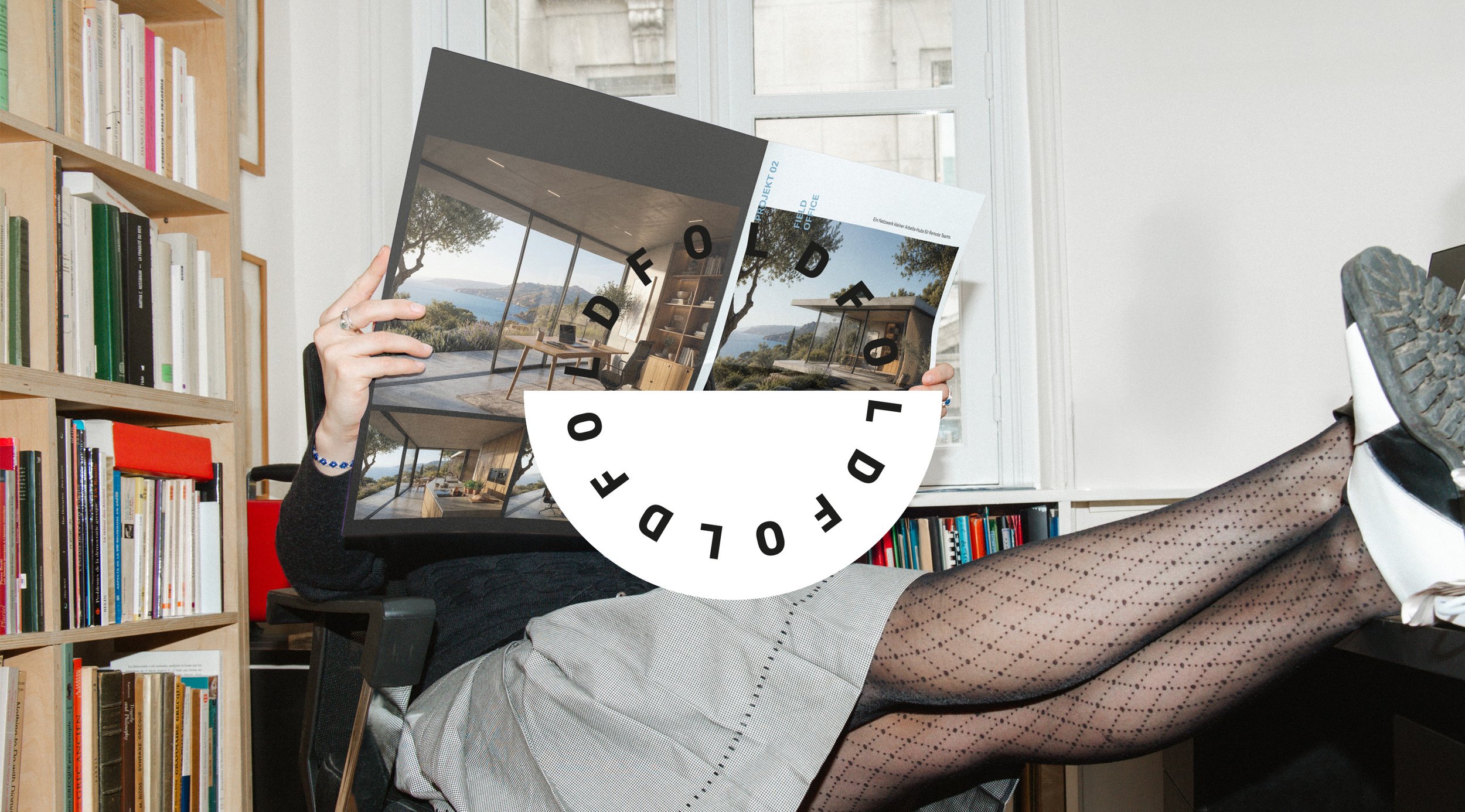 Person liest eine Broschüre mit einem modernen Innenarchitekturfoto, während sie mit den Beinen auf einem Stuhl liegt. Der Raum hat Bücherregale an der Wand und große Fenster im Hintergrund.