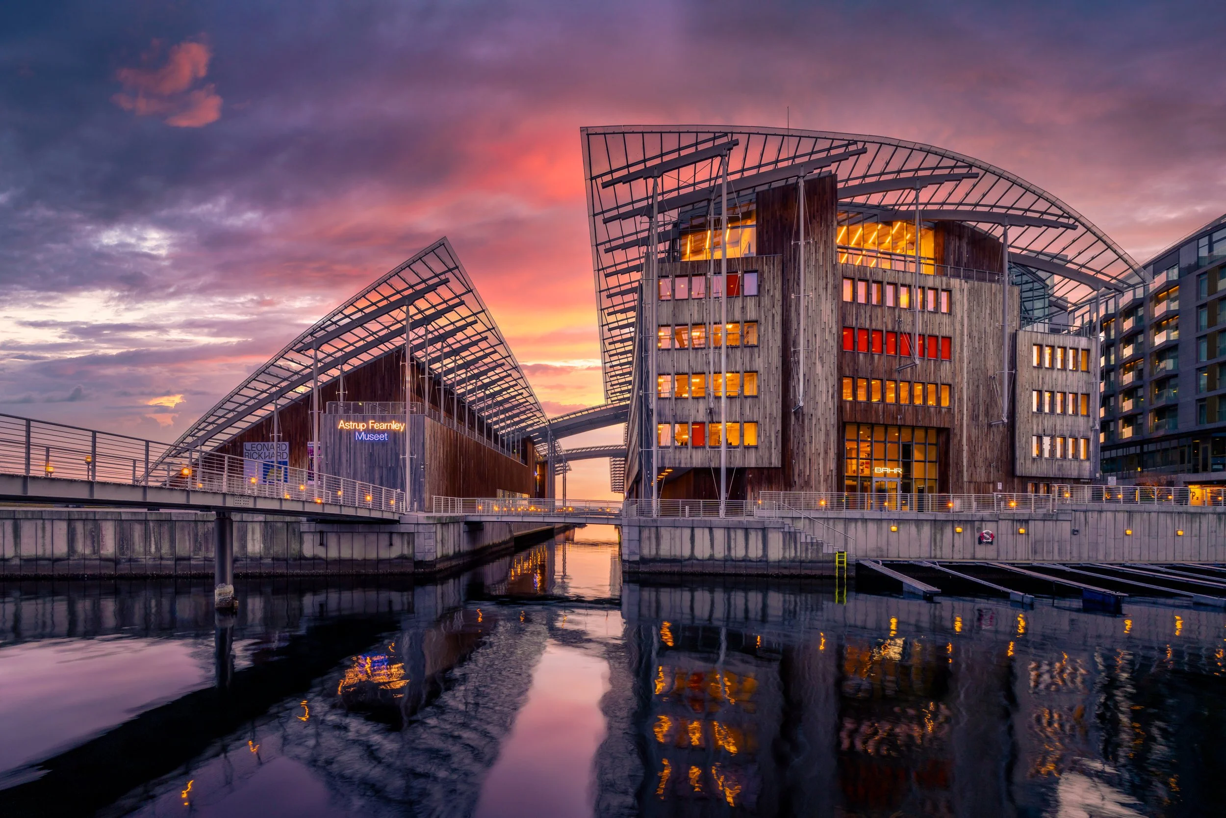 Astrup Fearnley Museum Of Modern Art:Modern city architecture at twilight with illuminated windows and reflections in water.