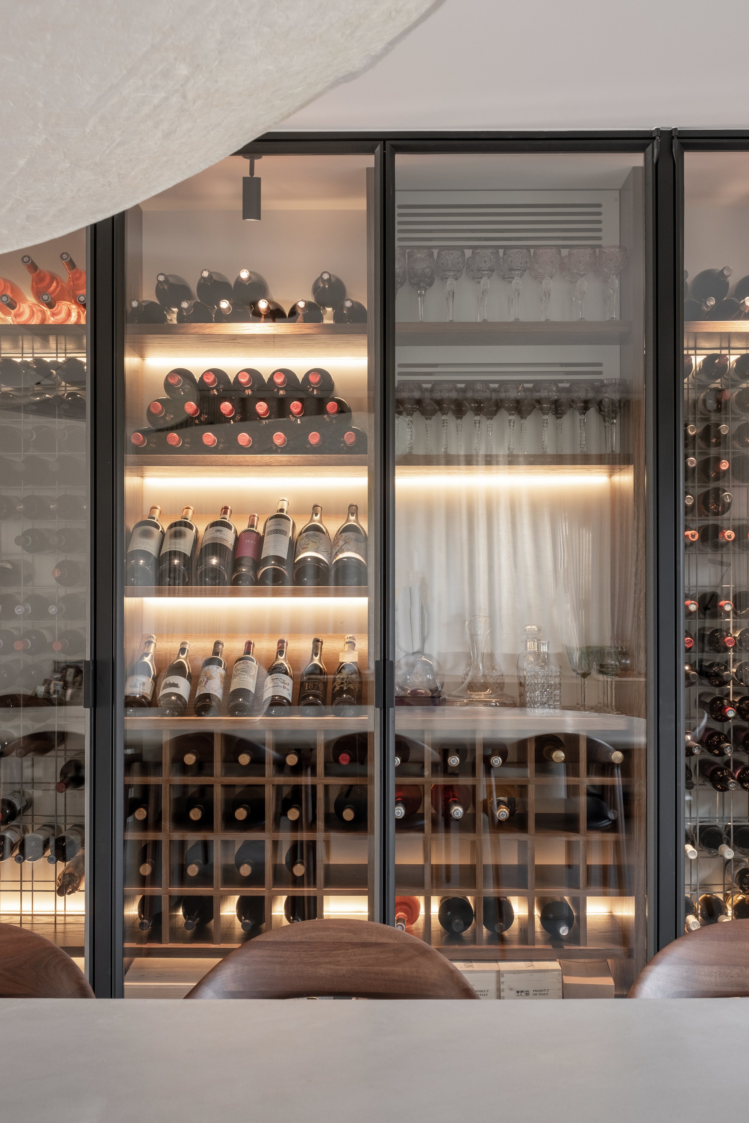 Wijnkast met wijnflessen en wijnkaren, glazen en decoratieve voorwerpen binnen.