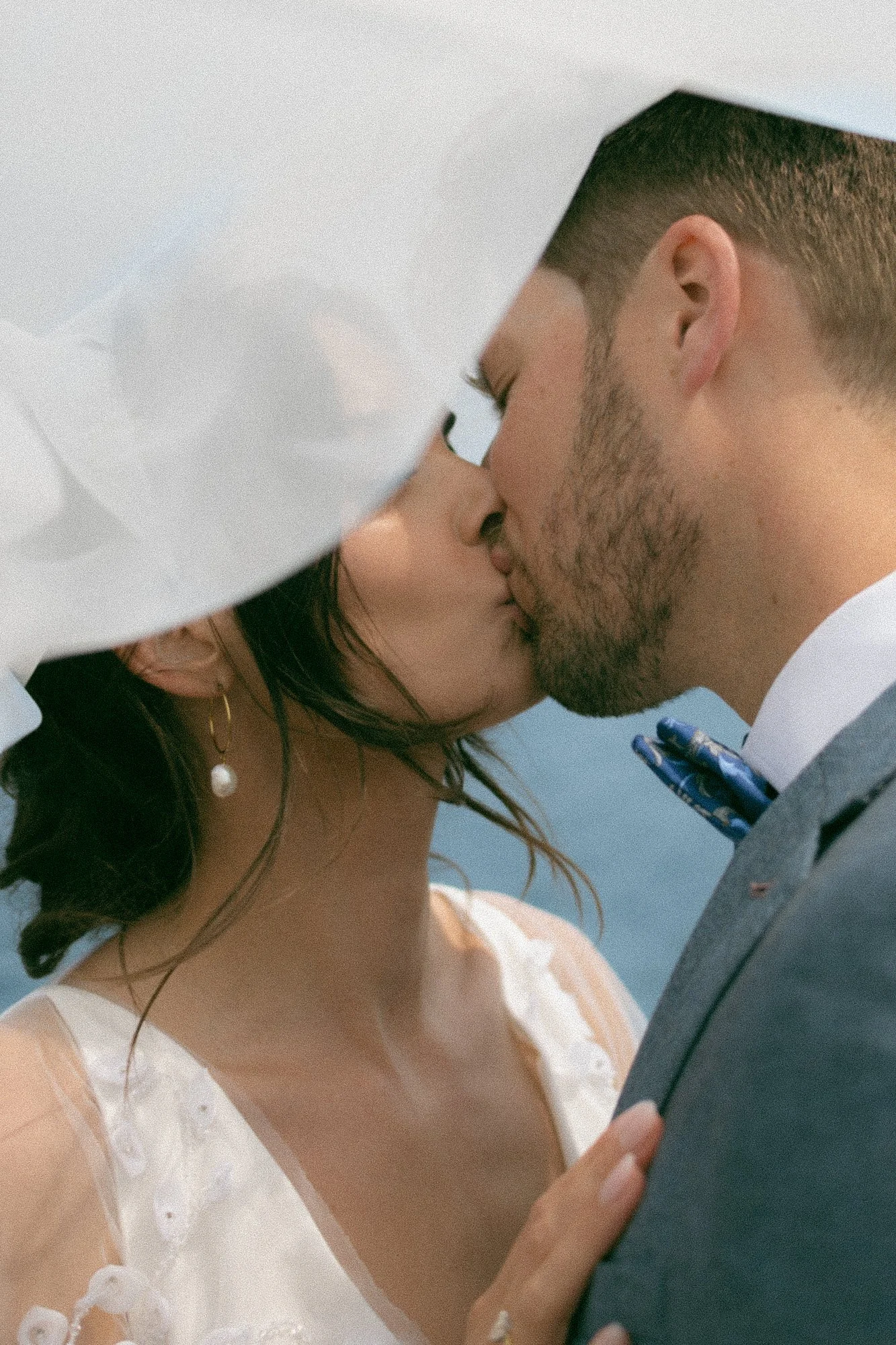 A bride and groom sharing a kiss during their wedding, with the bride in a white dress and the groom in a suit.
