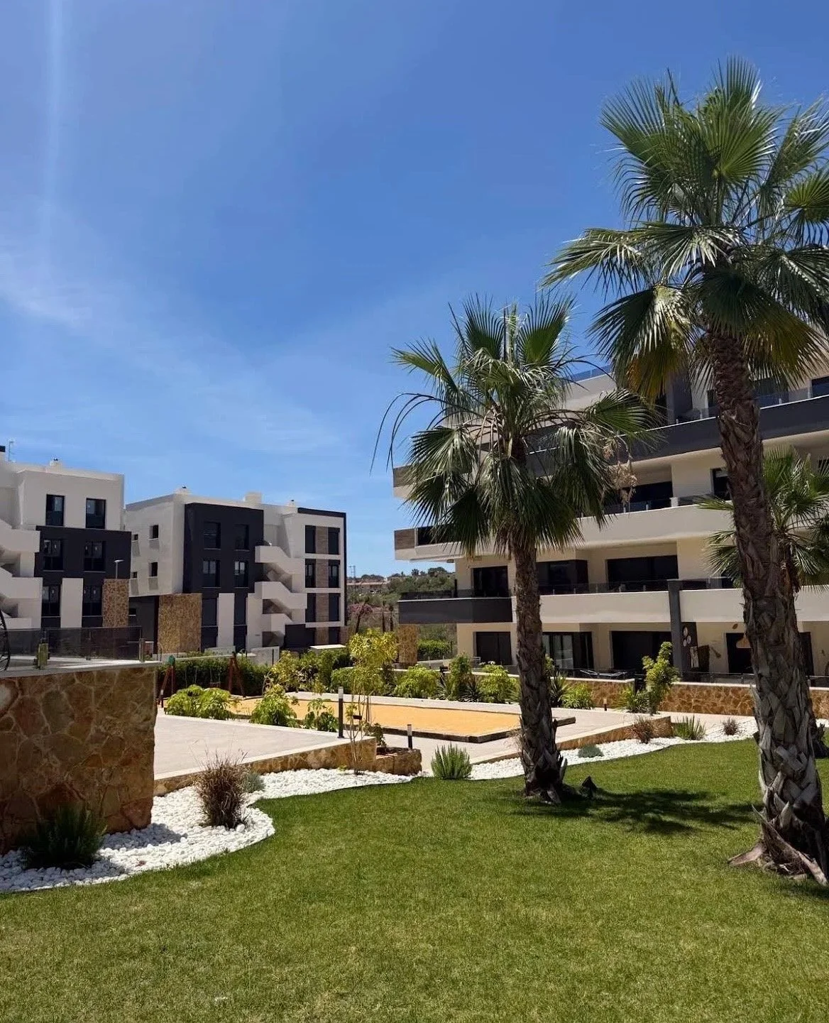 Groene tuin met palmbomen bij het appartementencomplex