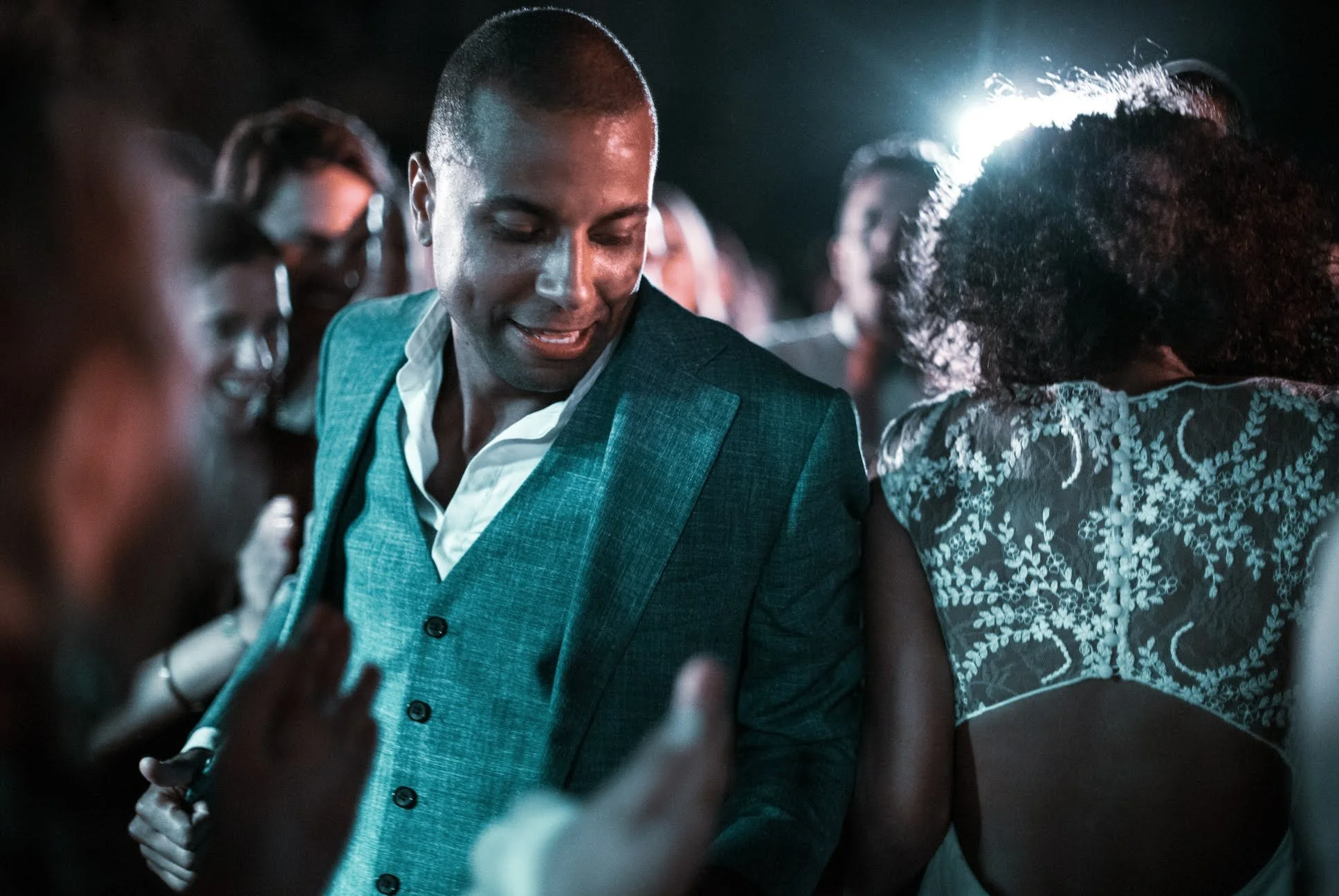 Groupe de personnes dansant lors d'une fête, ambiance sombre avec éclairage de scène.