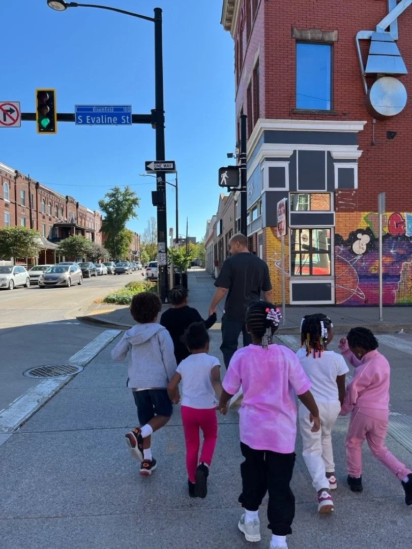 Preschool children practice safely crossing the street with their teachers during a Head Start traffic safety lesson.