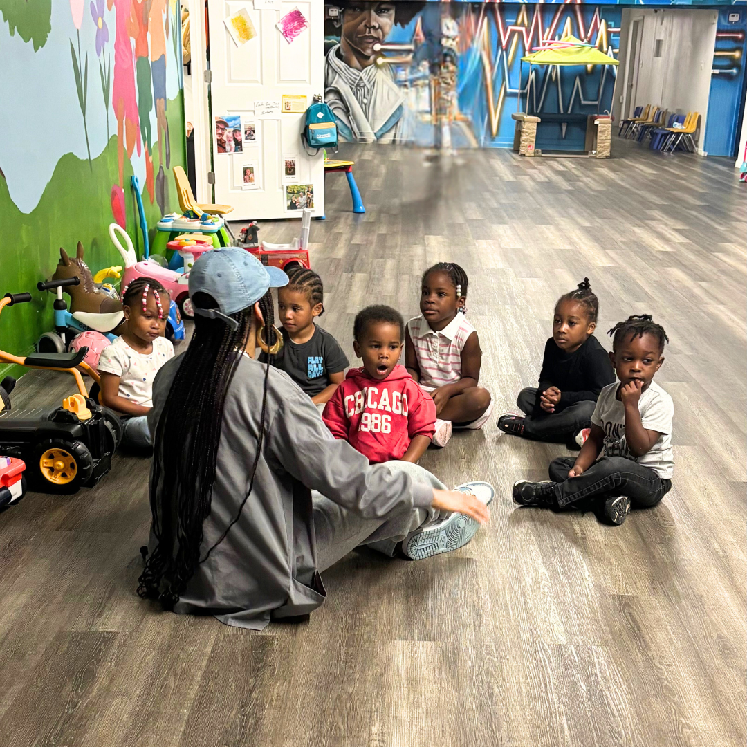 Preschool 2 is sitting down in the gross motor area for story time.