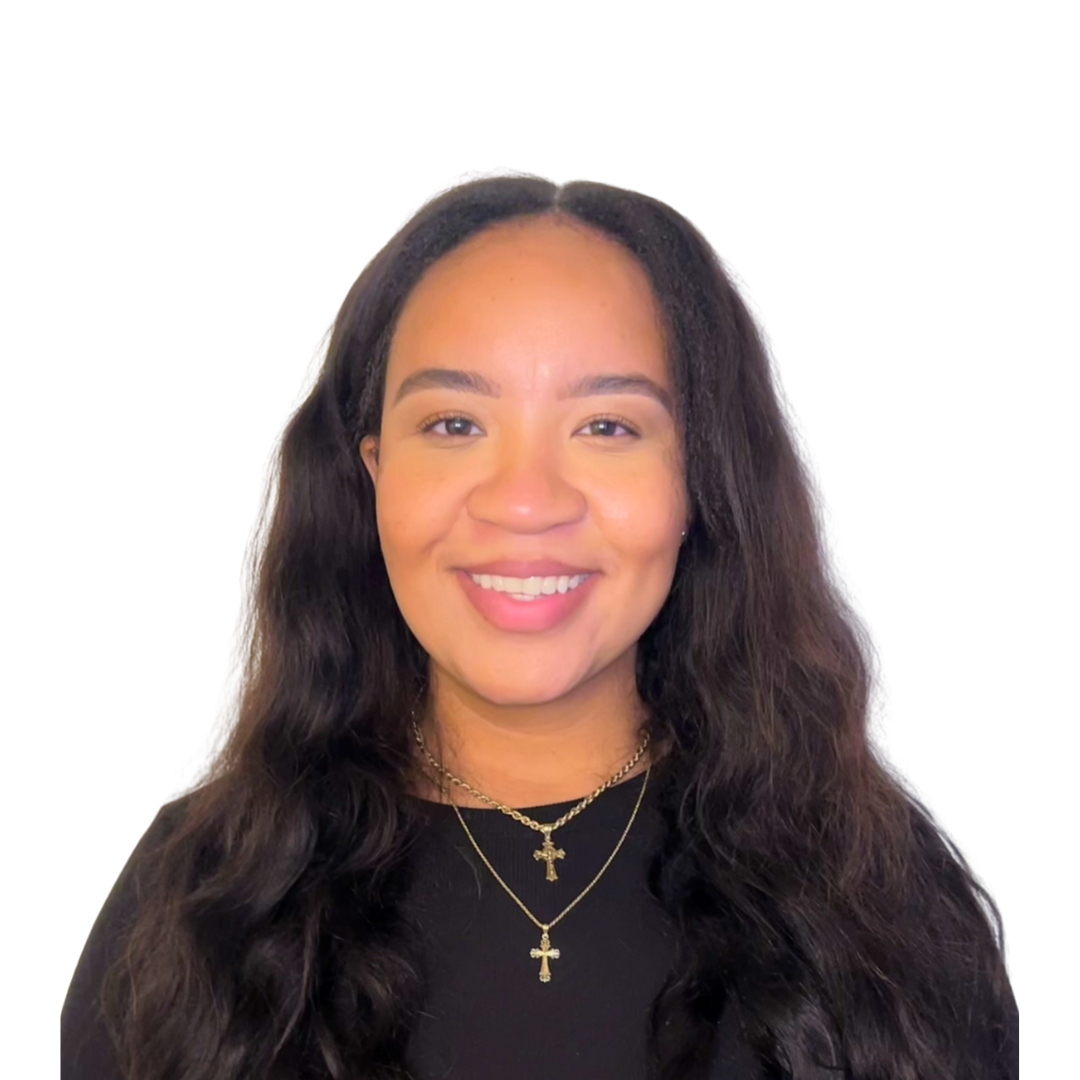 Miss. Kianna Ralph the Operations Manager wearing gold layered necklaces with crosses, black top, and posing against a white background.