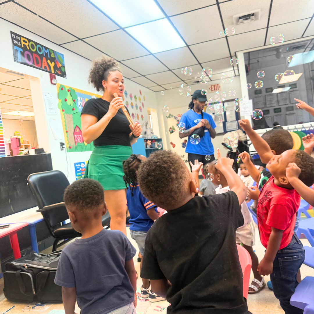 Preschool 3 class enjoying a visit from Reading Is Fundamental, with children excitedly reaching for bubbles as a guest engages them in a fun, interactive activity.