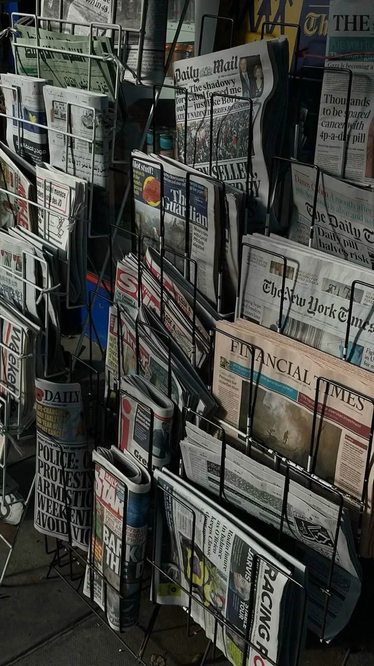 A display rack filled with various newspapers and magazines outside a newsstand.