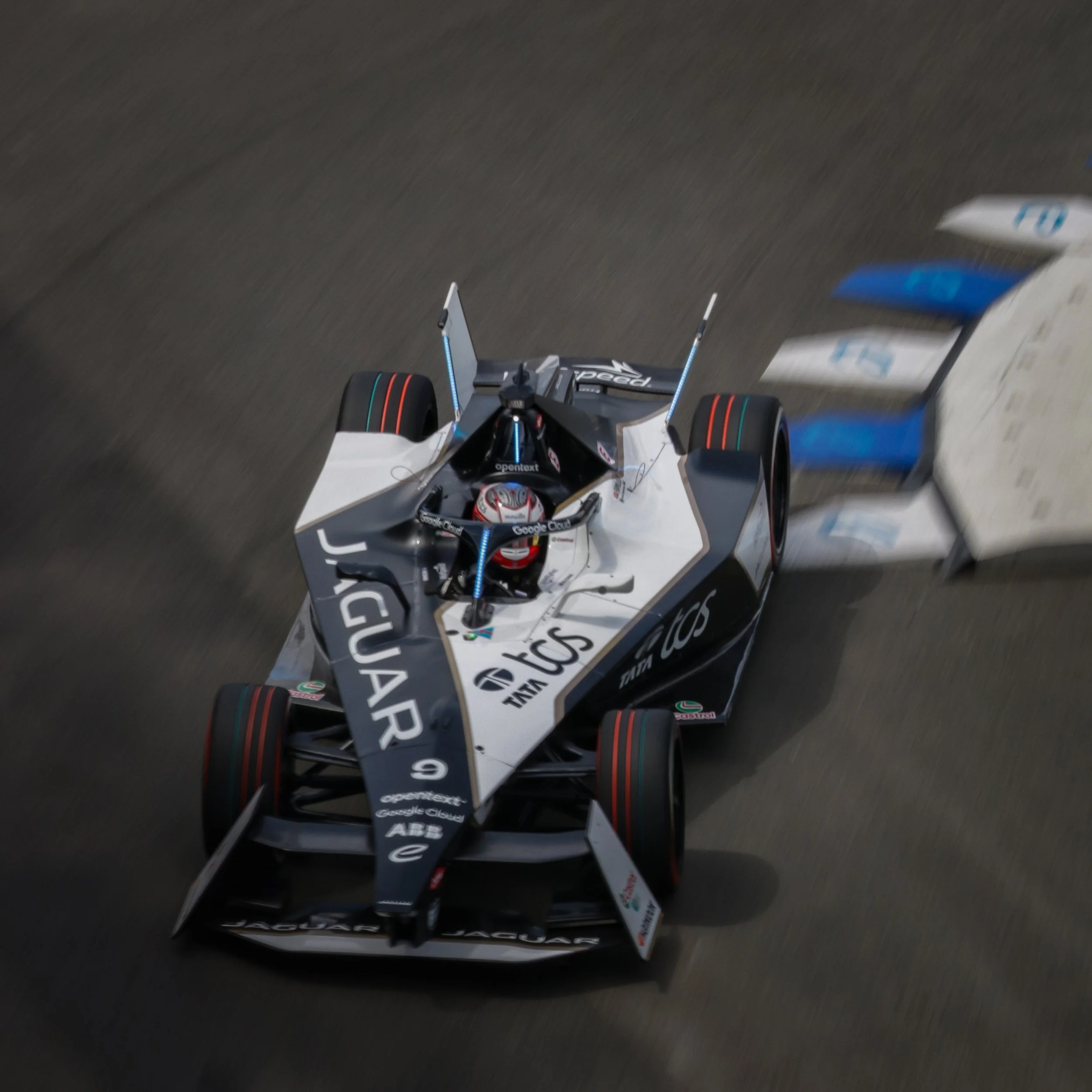 A racing car speeding on the track with a driver in a helmet visible inside the cockpit.