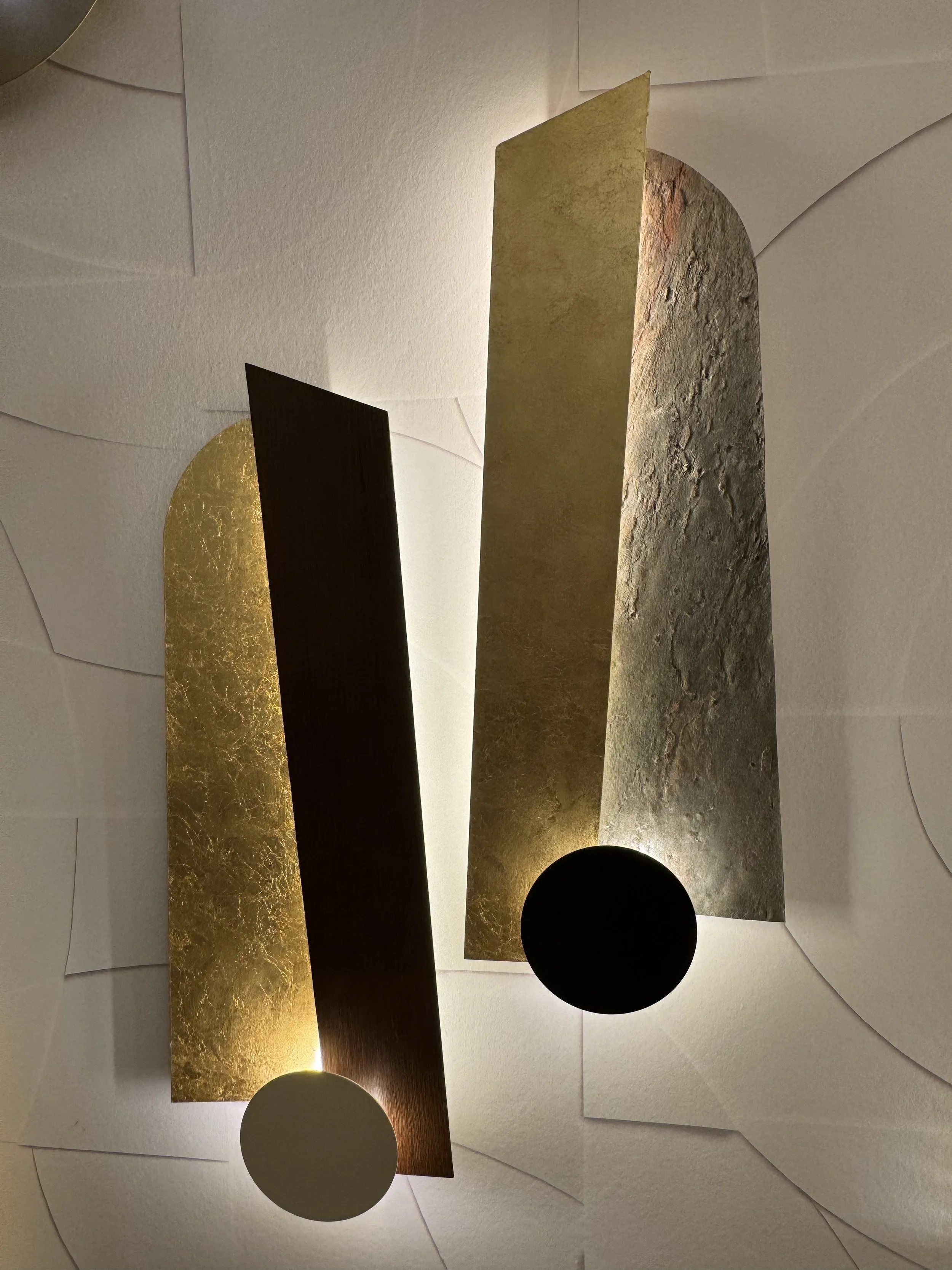 Loupe d'éclairage moderne avec des éléments en forme de plaques et de sphères noires et blanches en suspension sur un plafond.