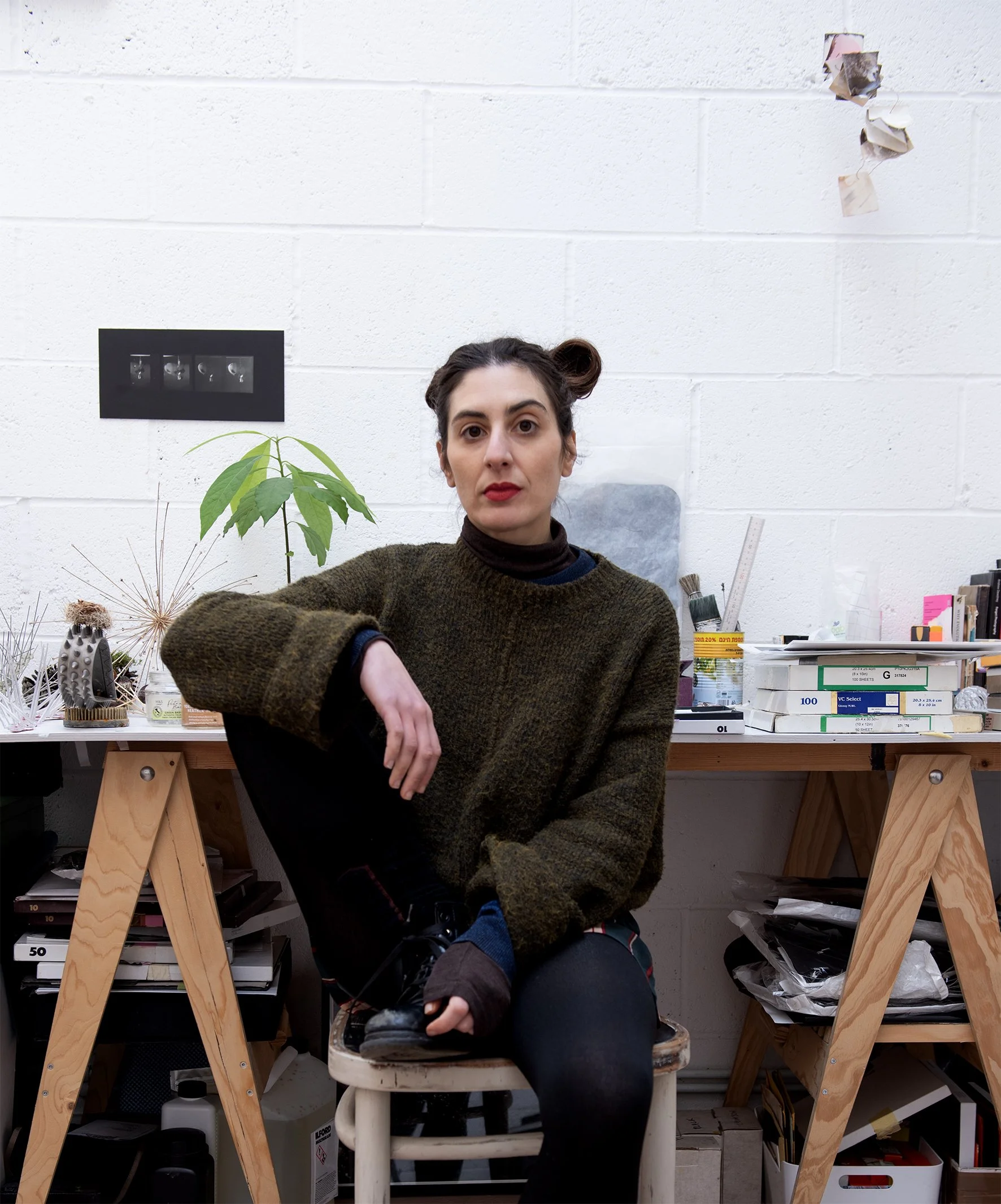 A portrait of a female artist in her studio in front of her working desk